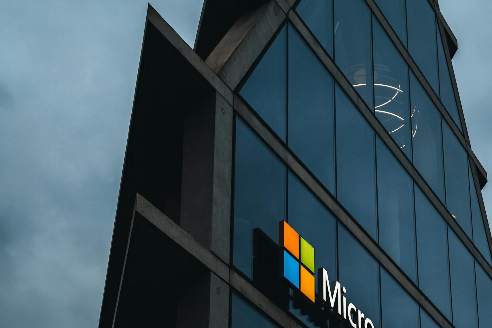 A modern Microsoft office skyscraper with glass facade against a cloudy evening sky.