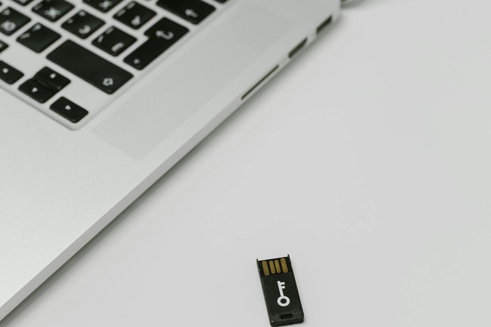 Close-up of a USB security key beside a laptop, emphasizing data encryption.